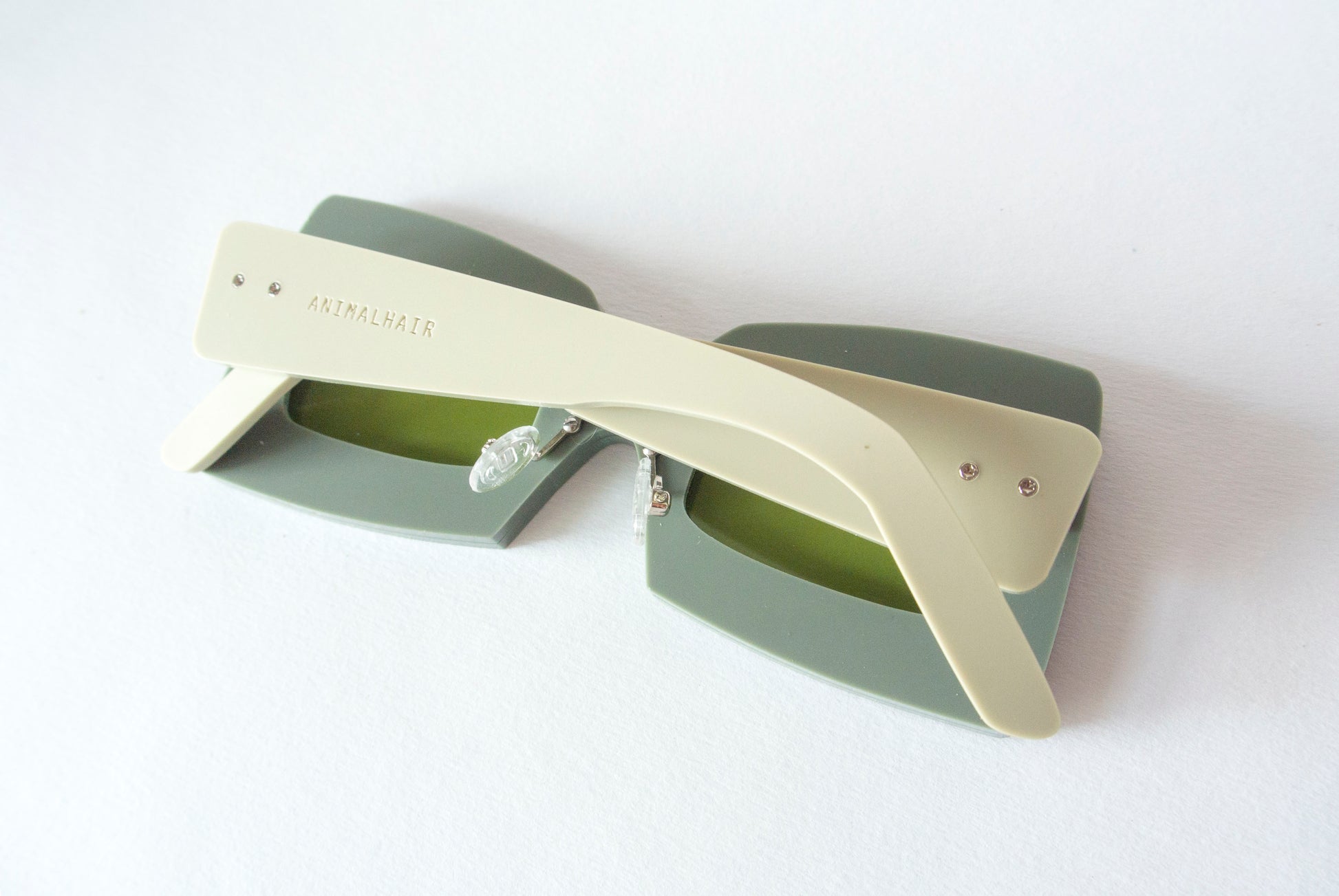 face down khaki square glasses with Animalhair logo etched into light green arms