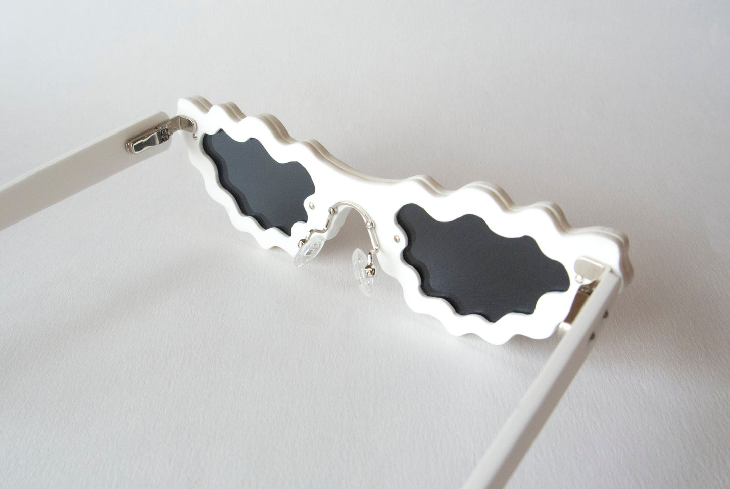 white cat eye sunglasses with black lenses and wobbly frames 