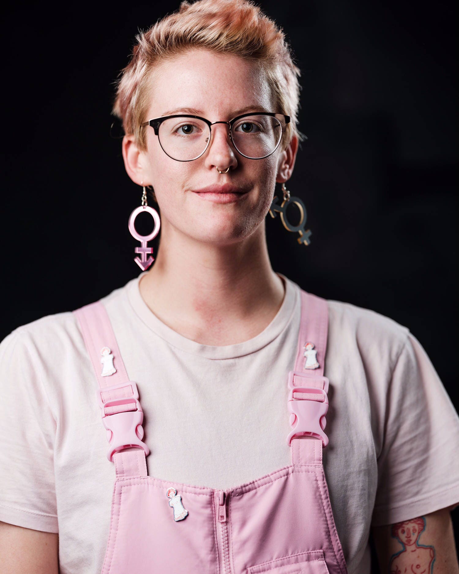 A man in pink overalls wears androgynous and bi-gender earrings by animalhair.
